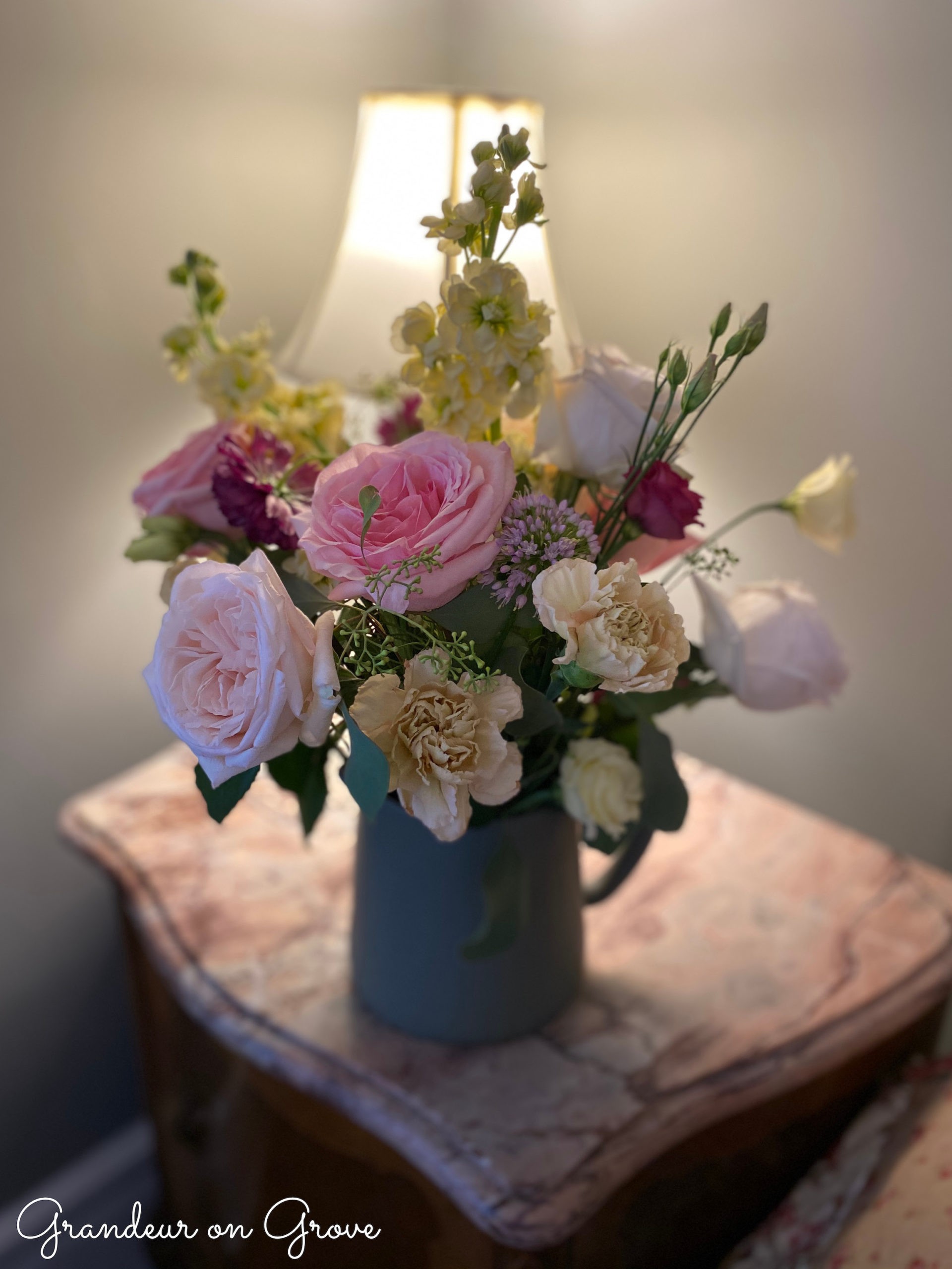 A floral arrangement with pink and yellow flowers in a green vase