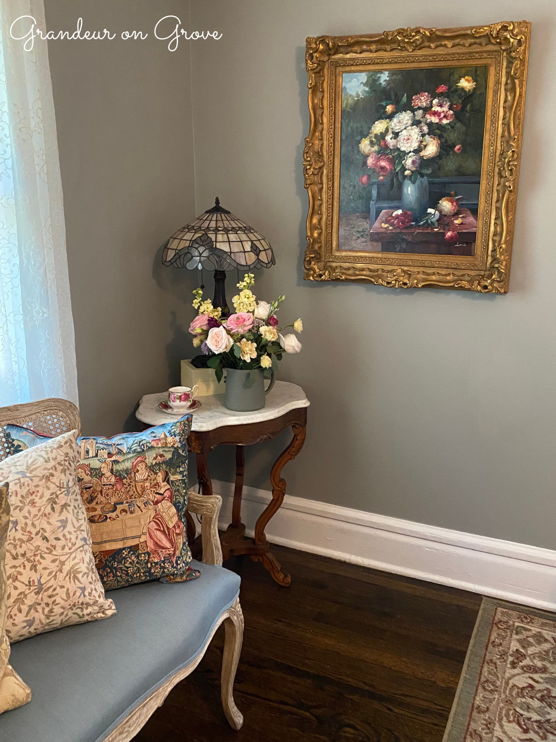 A floral arrangement looks similar to an oil painting that hangs beside it