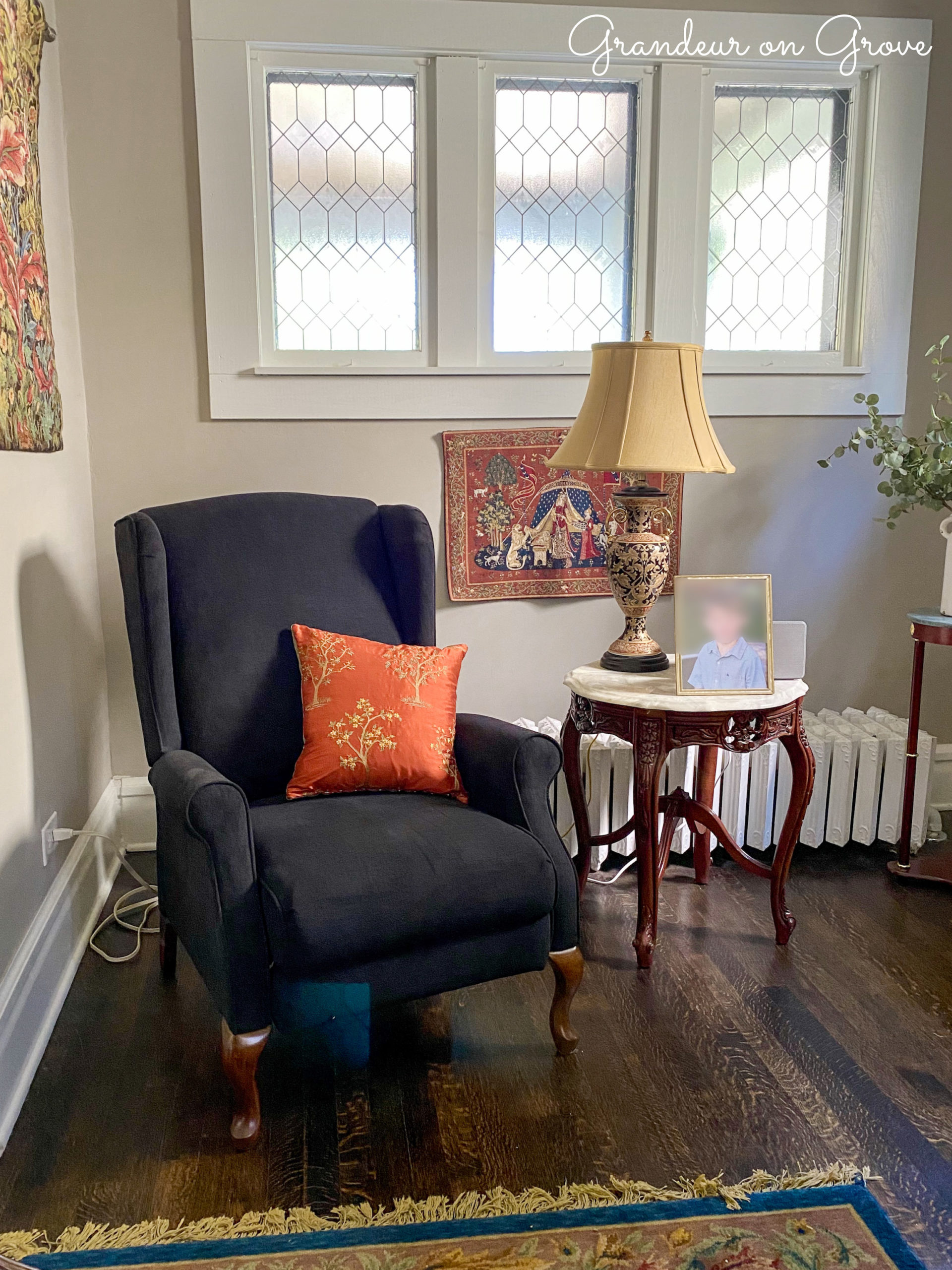 A living room with chair, pillow, lamp and tapestries