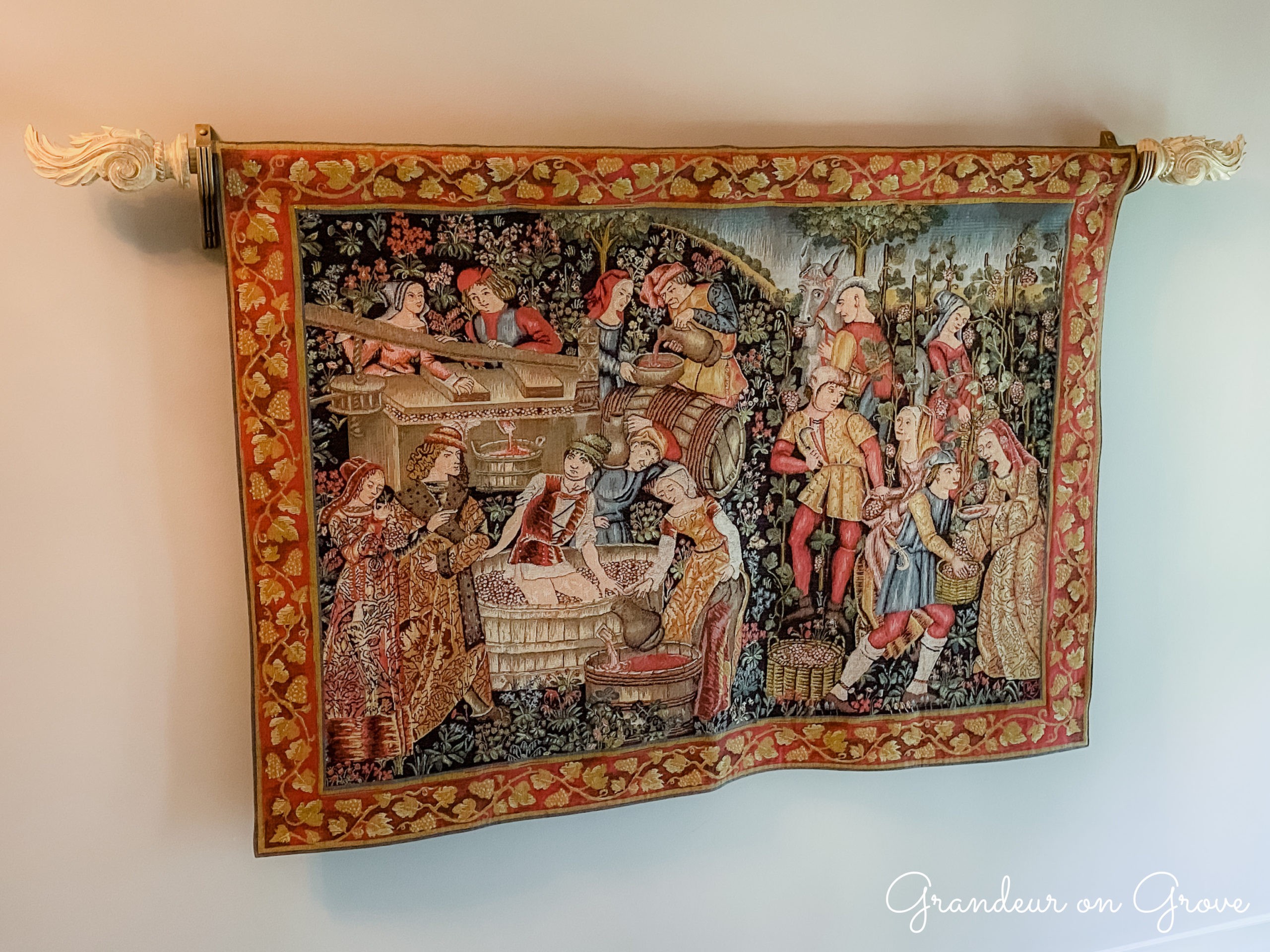 A large tapestry depicting people making wine
